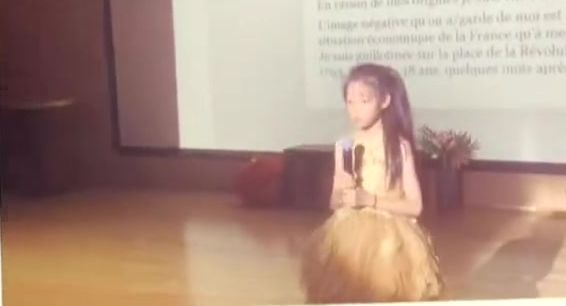 A girl alone on stage, microphone in hand, during the school show